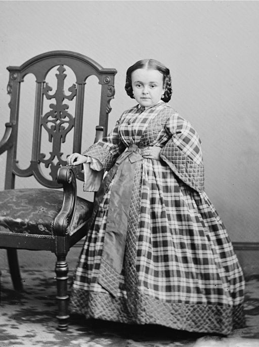 Lavinia Warren stands next to a chair.