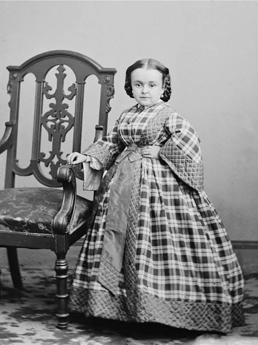 Lavinia Warren stands next to a chair.